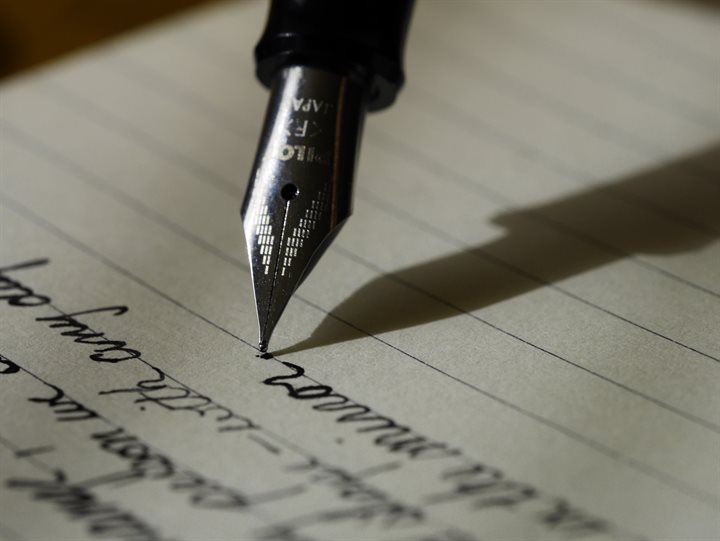 Een close-up van een vulpen met onleesbare woorden op papier.